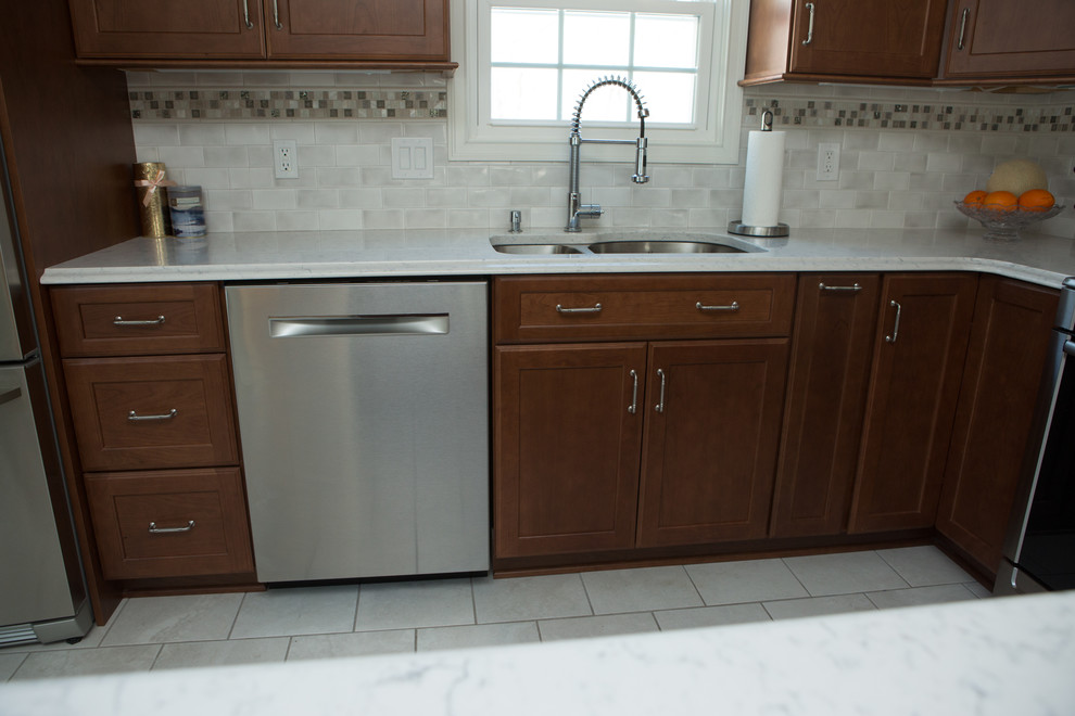 Mid-sized transitional l-shaped white floor and ceramic tile eat-in kitchen photo with an undermount sink, quartz countertops, white backsplash, stainless steel appliances, white countertops, shaker cabinets, medium tone wood cabinets, porcelain backsplash and a peninsula