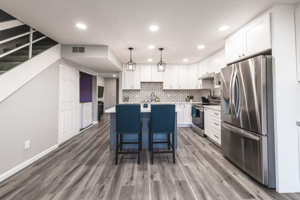Photo of a large modern l-shaped eat-in kitchen in San Francisco with an undermount sink, shaker cabinets, white cabinets, quartz benchtops, grey splashback, mosaic tile splashback, stainless steel appliances, vinyl floors, with island, grey floor and white benchtop.
