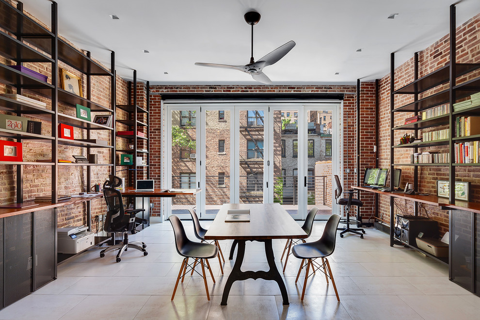 Large industrial home office in New York with a library, red walls, no fireplace, a built-in desk and white floor.