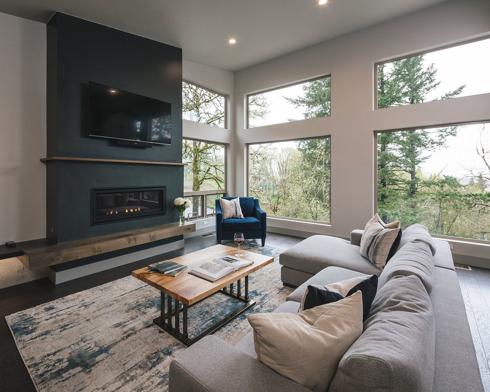 Photo of a mid-sized country open concept living room in Portland with white walls, dark hardwood floors, a standard fireplace, a plaster fireplace surround and a wall-mounted tv.