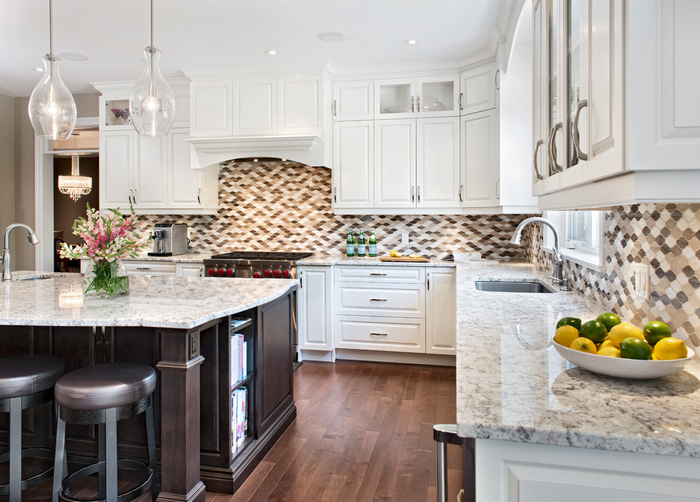Inspiration for a large mediterranean l-shaped eat-in kitchen in Ottawa with an undermount sink, raised-panel cabinets, white cabinets, granite benchtops, multi-coloured splashback, mosaic tile splashback, stainless steel appliances, dark hardwood floors, with island and brown floor.