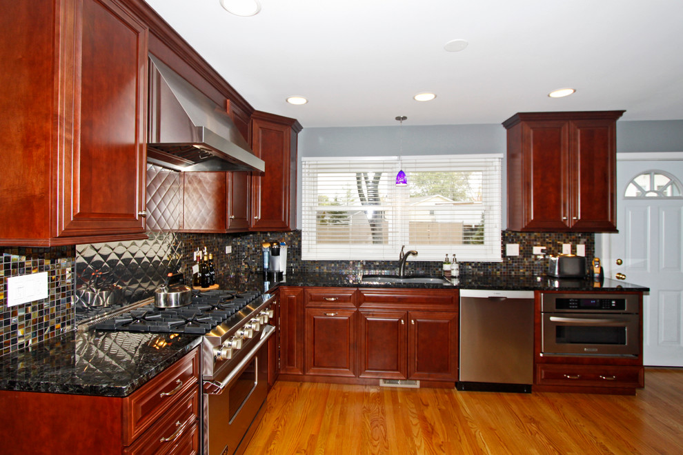 Inspiration for a mid-sized transitional u-shaped medium tone wood floor eat-in kitchen remodel in Chicago with an undermount sink, raised-panel cabinets, medium tone wood cabinets, granite countertops, multicolored backsplash, glass tile backsplash, stainless steel appliances and a peninsula