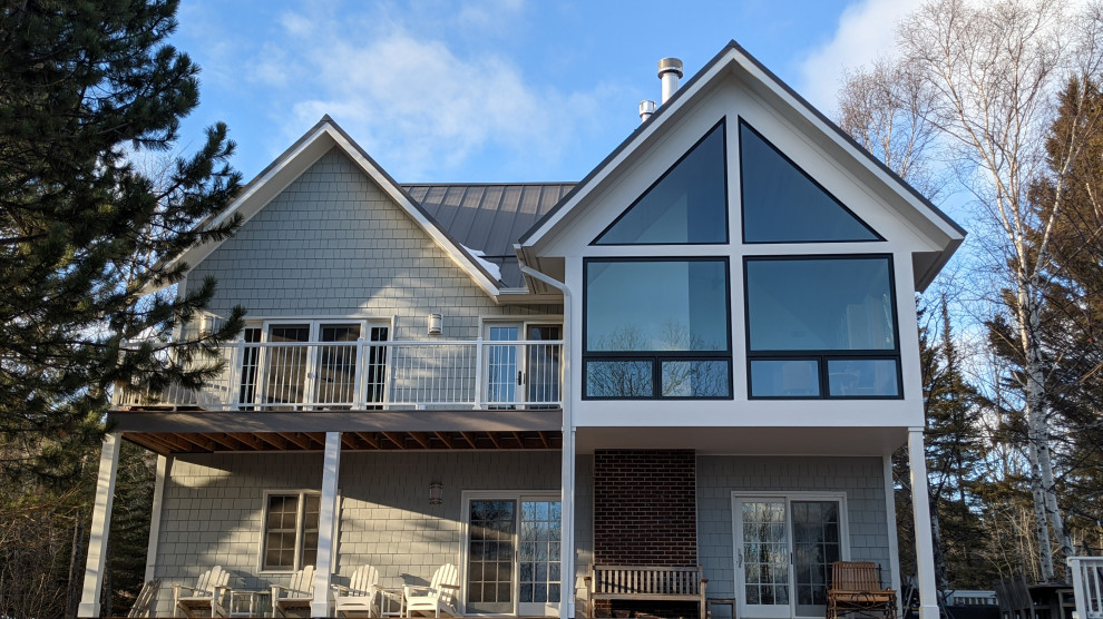 Diseño de fachada de casa gris costera de tamaño medio de dos plantas con revestimiento de aglomerado de cemento, tejado a dos aguas y tejado de metal