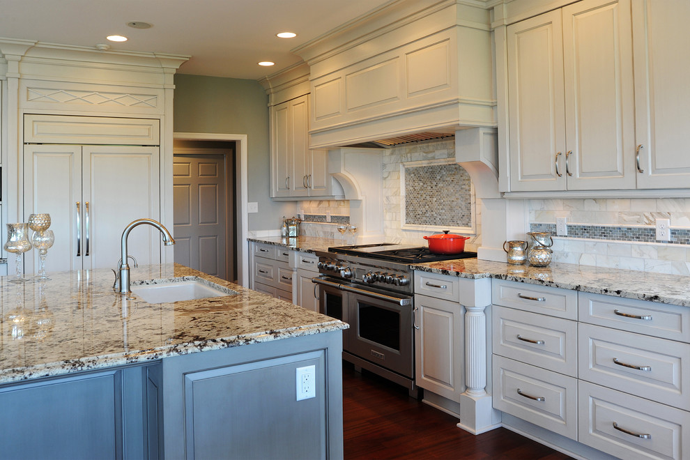 Open concept kitchen - mid-sized transitional l-shaped dark wood floor open concept kitchen idea with an undermount sink, raised-panel cabinets, white cabinets, granite countertops, white backsplash, mosaic tile backsplash, stainless steel appliances and an island