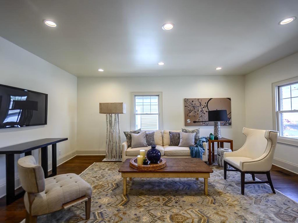 This is an example of a large transitional enclosed living room in Milwaukee with white walls, dark hardwood floors, no fireplace and a wall-mounted tv.