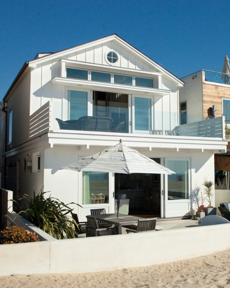 This is an example of a small beach style two-storey white house exterior in Orange County with wood siding, a gable roof and a shingle roof.
