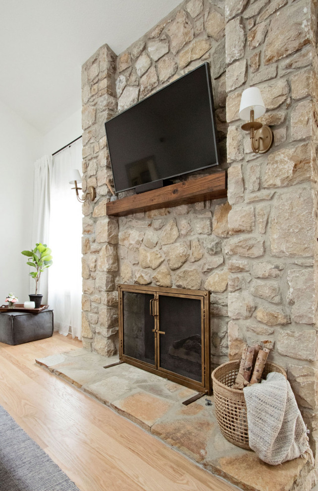Foto de dormitorio principal y abovedado tradicional renovado grande con paredes blancas, suelo de madera clara, chimenea de doble cara, piedra de revestimiento y suelo marrón