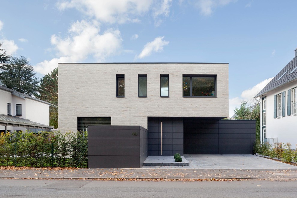 This is an example of a mid-sized contemporary two-storey beige exterior in Cologne with stone veneer and a flat roof.
