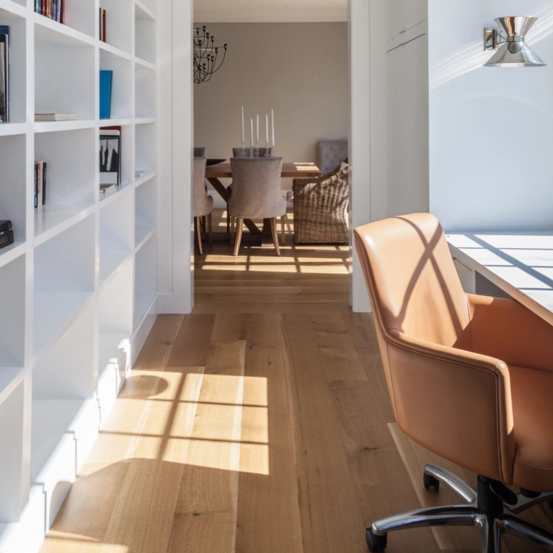 Ejemplo de despacho tradicional con biblioteca, suelo de madera clara y escritorio empotrado