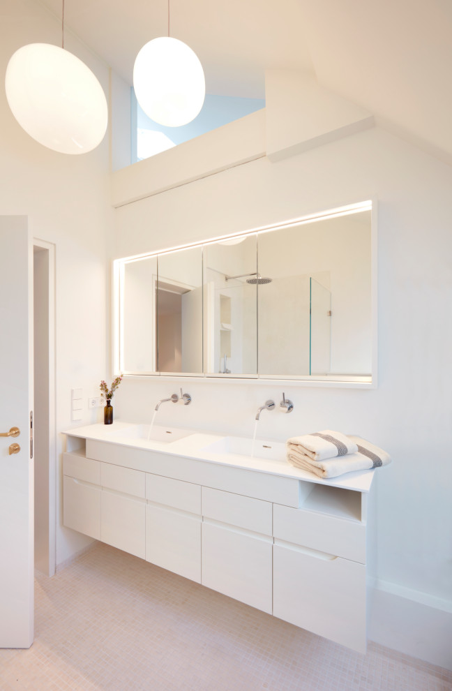 Inredning av ett modernt stort vit vitt badrum, med släta luckor, vita skåp, ett fristående badkar, en öppen dusch, en vägghängd toalettstol, vita väggar, mosaikgolv, ett integrerad handfat, träbänkskiva, beiget golv och med dusch som är öppen