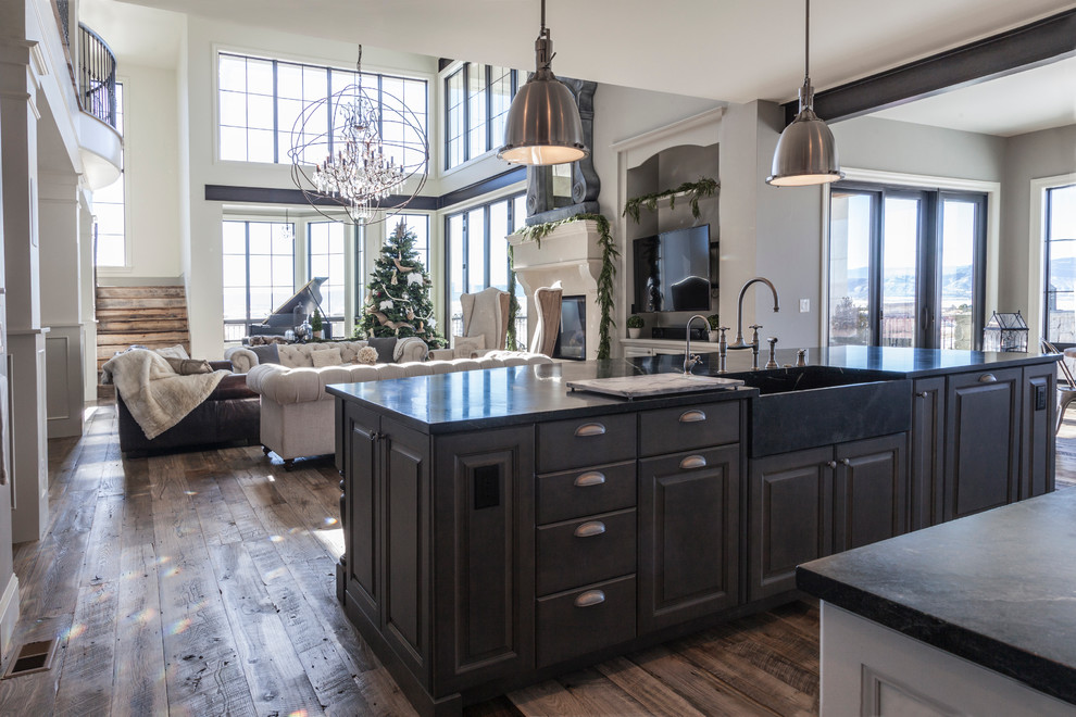 Transitional medium tone wood floor kitchen photo in Denver with a farmhouse sink, raised-panel cabinets, white cabinets, soapstone countertops, white backsplash, subway tile backsplash, stainless steel appliances and an island