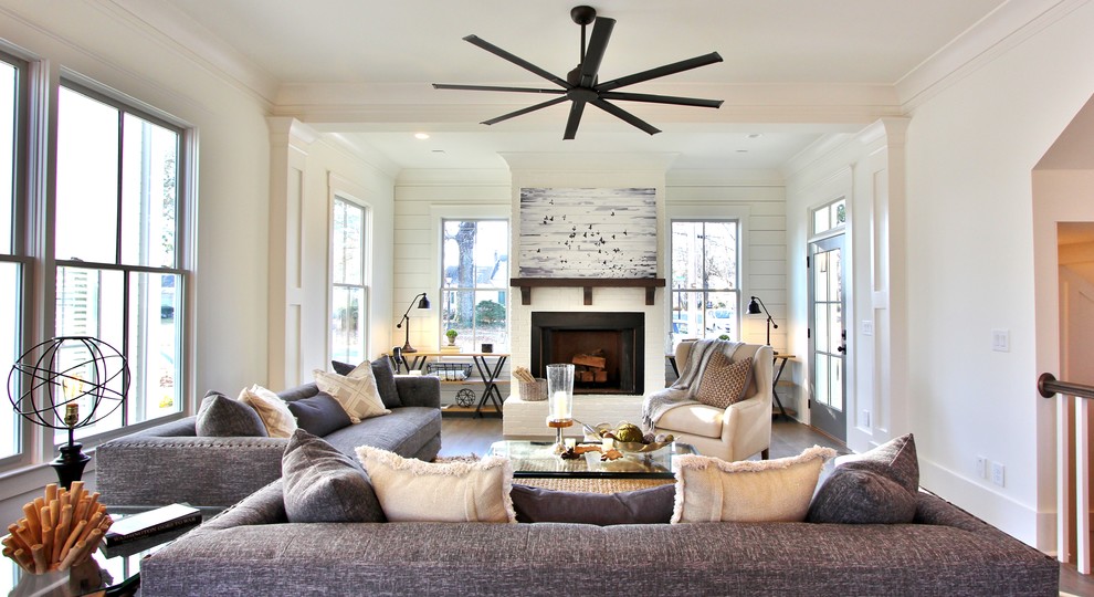 Photo of a country formal open concept living room in Atlanta with white walls, medium hardwood floors, a standard fireplace, a brick fireplace surround and brown floor.
