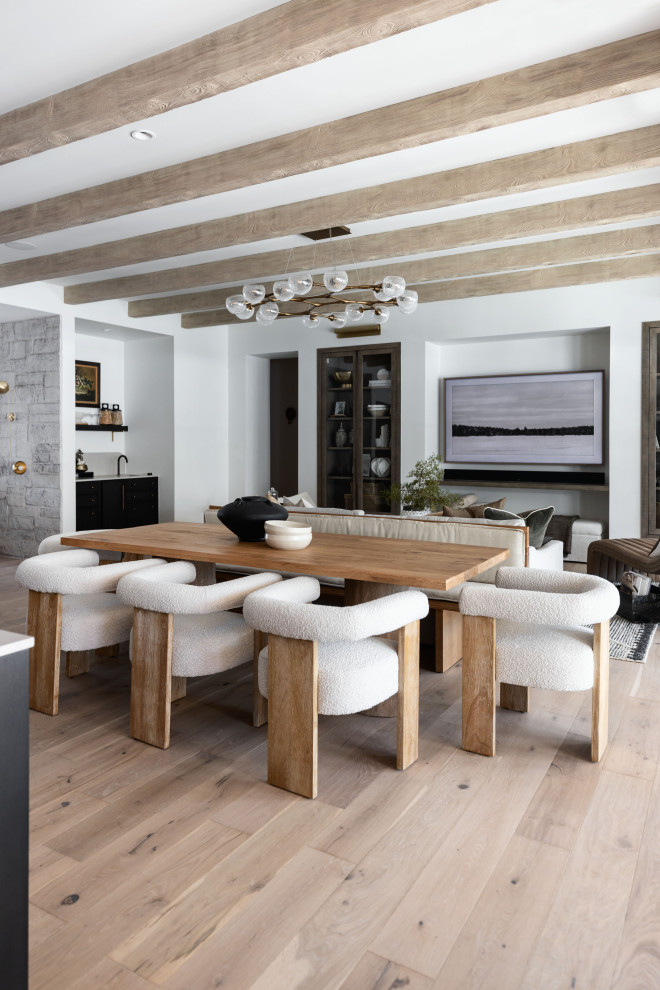 This is an example of a transitional open plan dining in Phoenix with white walls, light hardwood floors, beige floor and exposed beam.