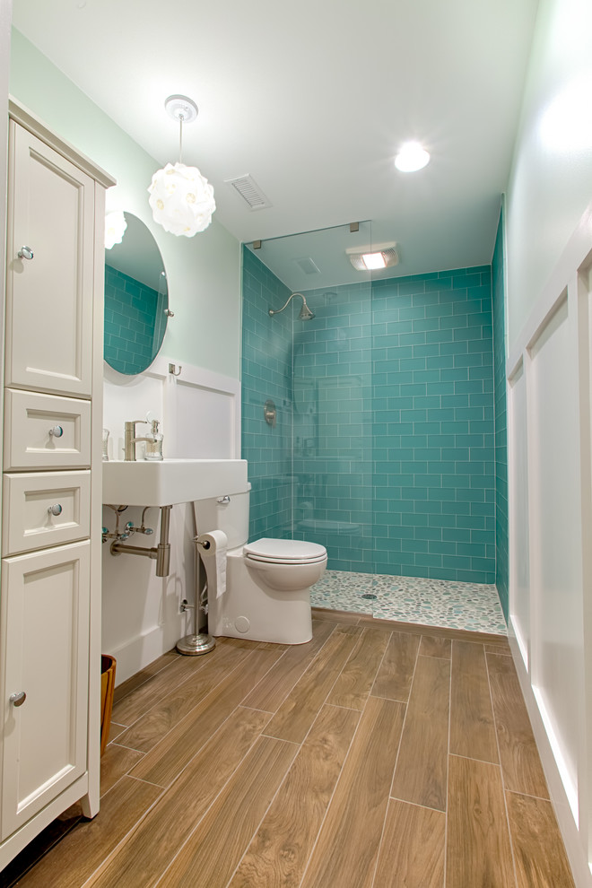 This is an example of a mid-sized beach style bathroom in Raleigh with a curbless shower, blue tile, glass tile, ceramic floors, a wall-mount sink, brown floor and an open shower.