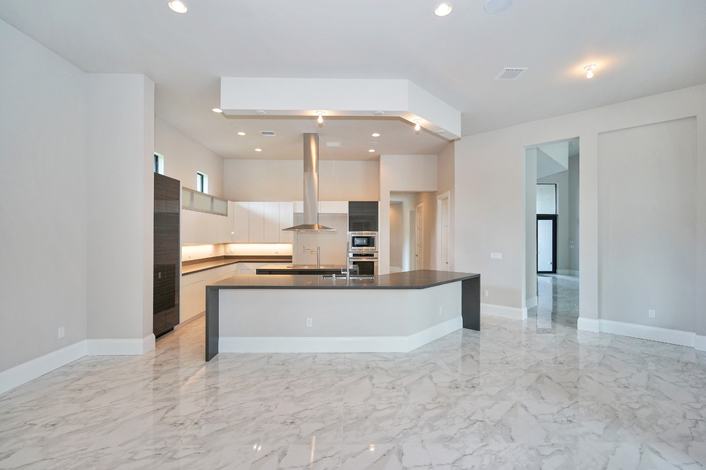 This is an example of a large contemporary l-shaped open plan kitchen in Miami with an undermount sink, flat-panel cabinets, white cabinets, concrete benchtops, beige splashback, stainless steel appliances, marble floors, multiple islands and white floor.