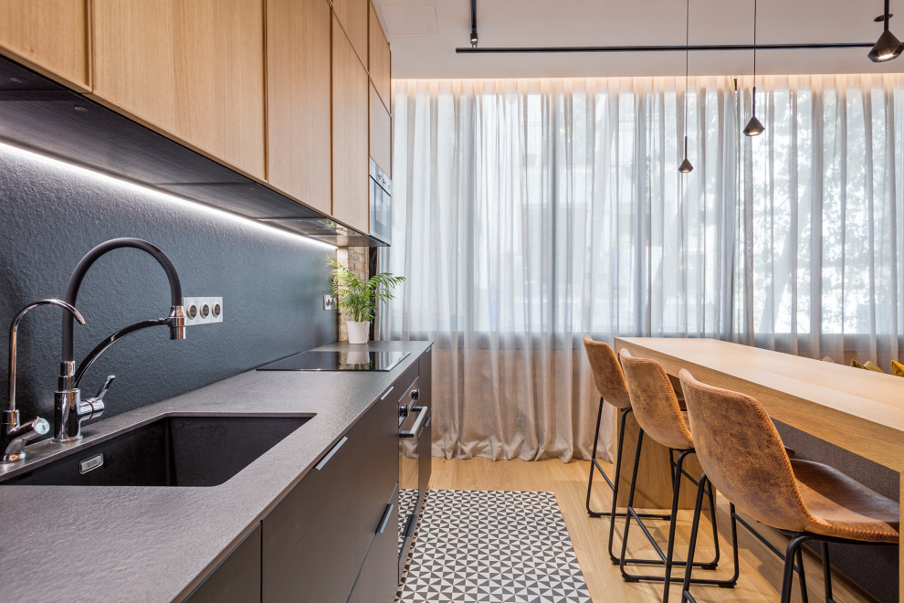 Example of a mid-sized urban single-wall medium tone wood floor and black floor open concept kitchen design in Barcelona with an undermount sink, flat-panel cabinets, medium tone wood cabinets, quartz countertops, black backsplash, quartz backsplash, stainless steel appliances, an island and black countertops