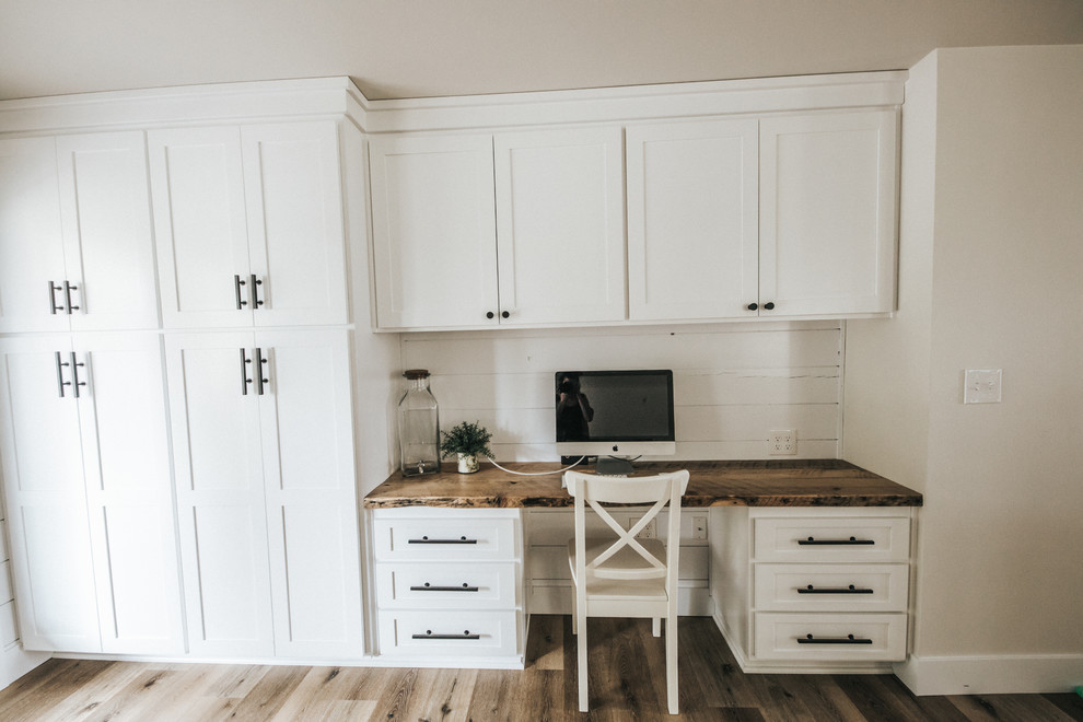 This is an example of a mid-sized arts and crafts l-shaped eat-in kitchen in Other with an undermount sink, shaker cabinets, white cabinets, quartzite benchtops, white splashback, marble splashback, stainless steel appliances, medium hardwood floors, with island, brown floor and white benchtop.
