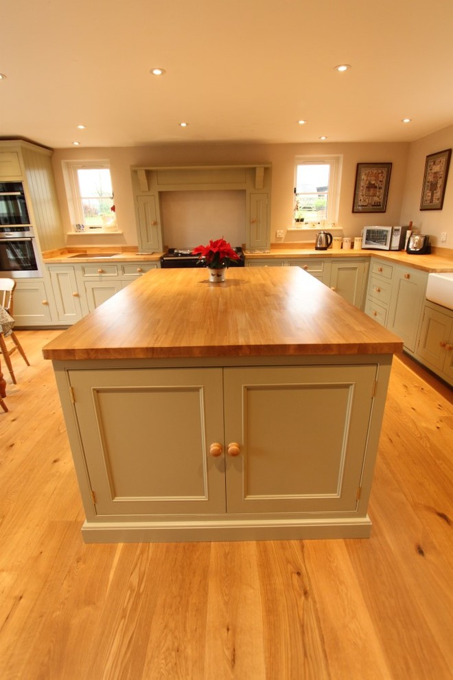 Inspiration for a large country l-shaped eat-in kitchen in Hampshire with a farmhouse sink, shaker cabinets, green cabinets, wood benchtops, panelled appliances, medium hardwood floors and with island.