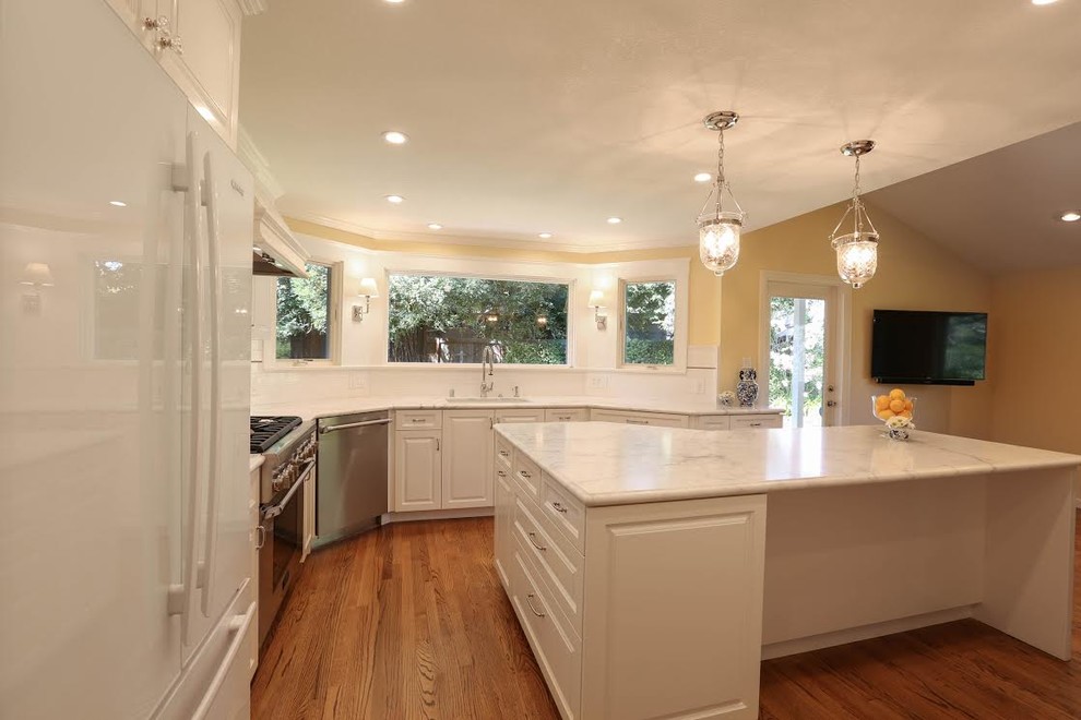 Mid-sized transitional u-shaped light wood floor enclosed kitchen photo in San Francisco with an undermount sink, beaded inset cabinets, white cabinets, marble countertops, white backsplash, subway tile backsplash, white appliances and an island