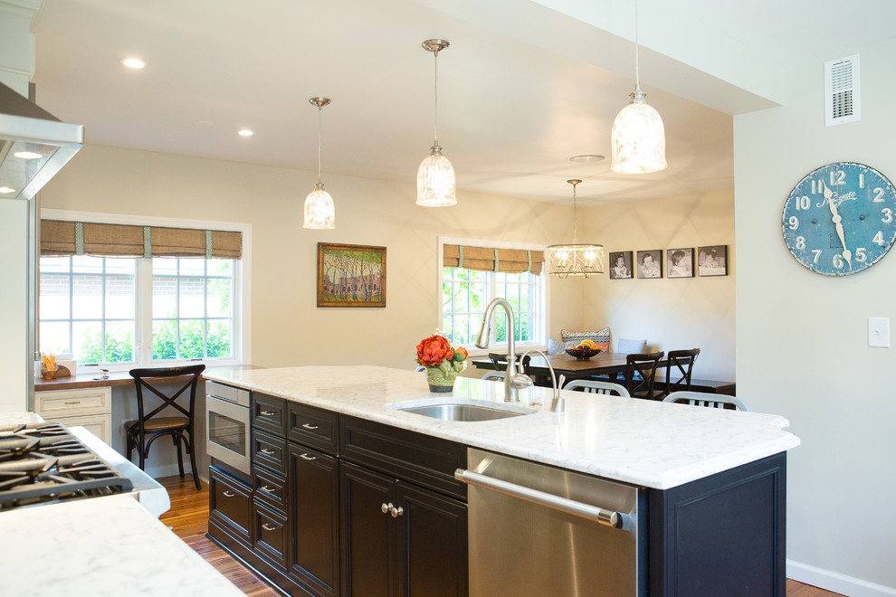 Example of a large transitional galley medium tone wood floor eat-in kitchen design with an undermount sink, recessed-panel cabinets, black cabinets, quartz countertops, brick backsplash, stainless steel appliances and an island