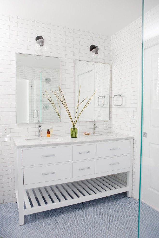 This is an example of a modern master bathroom in New York with beaded inset cabinets, white cabinets, a drop-in tub, an open shower, a two-piece toilet, white tile, subway tile, white walls, a drop-in sink, marble benchtops, blue floor, a hinged shower door, white benchtops, a double vanity and a freestanding vanity.