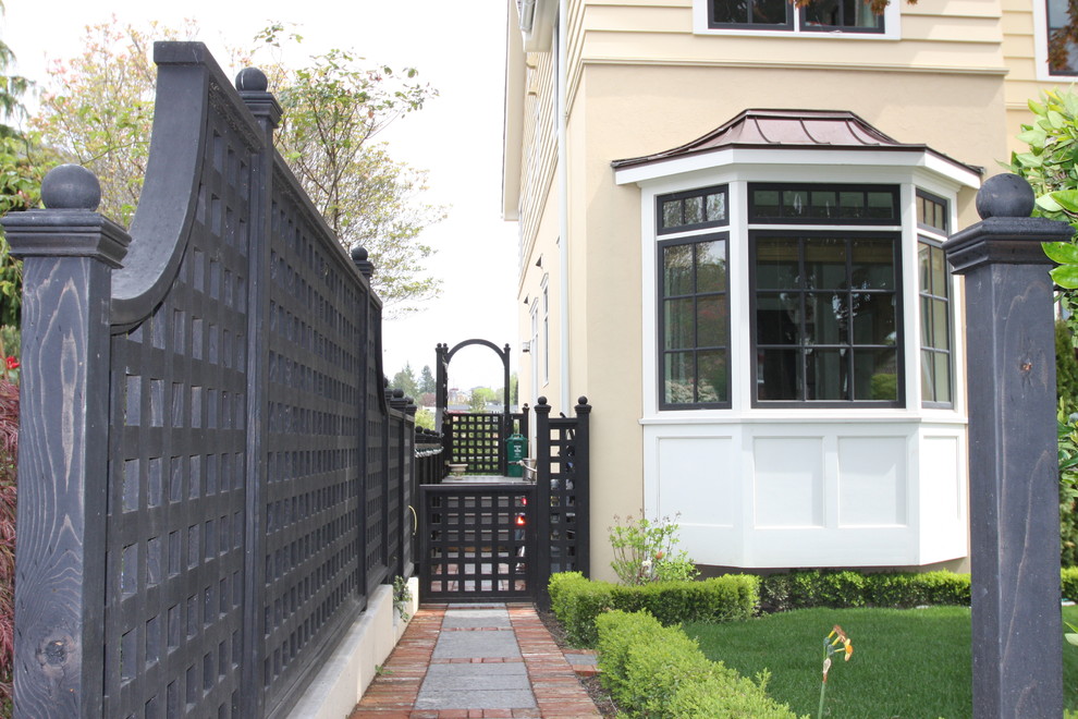 This is an example of a large traditional front yard full sun formal garden in Seattle with natural stone pavers and with a gate.