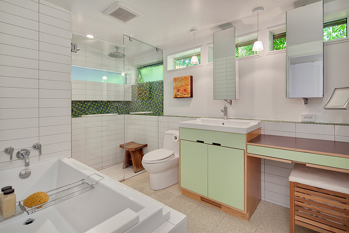 This is an example of a small contemporary master bathroom in Seattle with flat-panel cabinets, green cabinets, a corner tub, an alcove shower, a one-piece toilet, beige tile, white walls, a drop-in sink and wood benchtops.