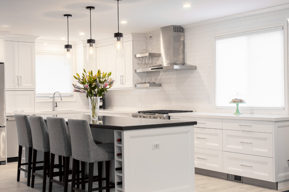 Large transitional l-shaped vinyl floor and white floor open concept kitchen photo in Toronto with an undermount sink, recessed-panel cabinets, white cabinets, quartz countertops, white backsplash, ceramic backsplash, stainless steel appliances, an island and white countertops