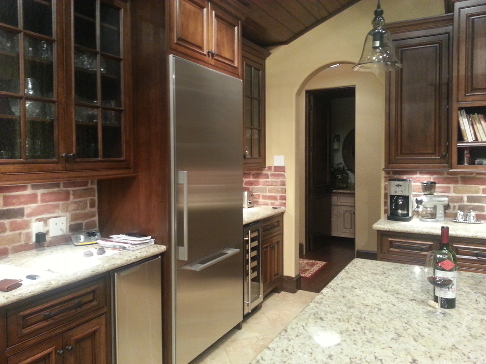 Eat-in kitchen - large rustic u-shaped porcelain tile eat-in kitchen idea in Houston with an undermount sink, raised-panel cabinets, dark wood cabinets, granite countertops, red backsplash, brick backsplash, stainless steel appliances and two islands