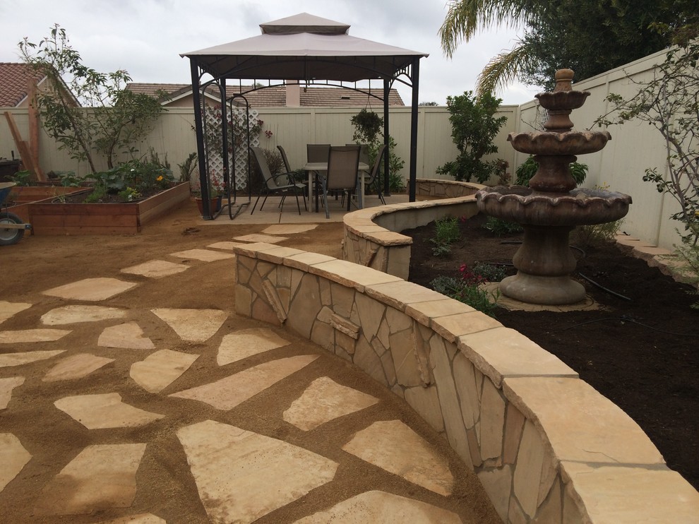 Photo of a large traditional backyard full sun garden for spring in Los Angeles with natural stone pavers.