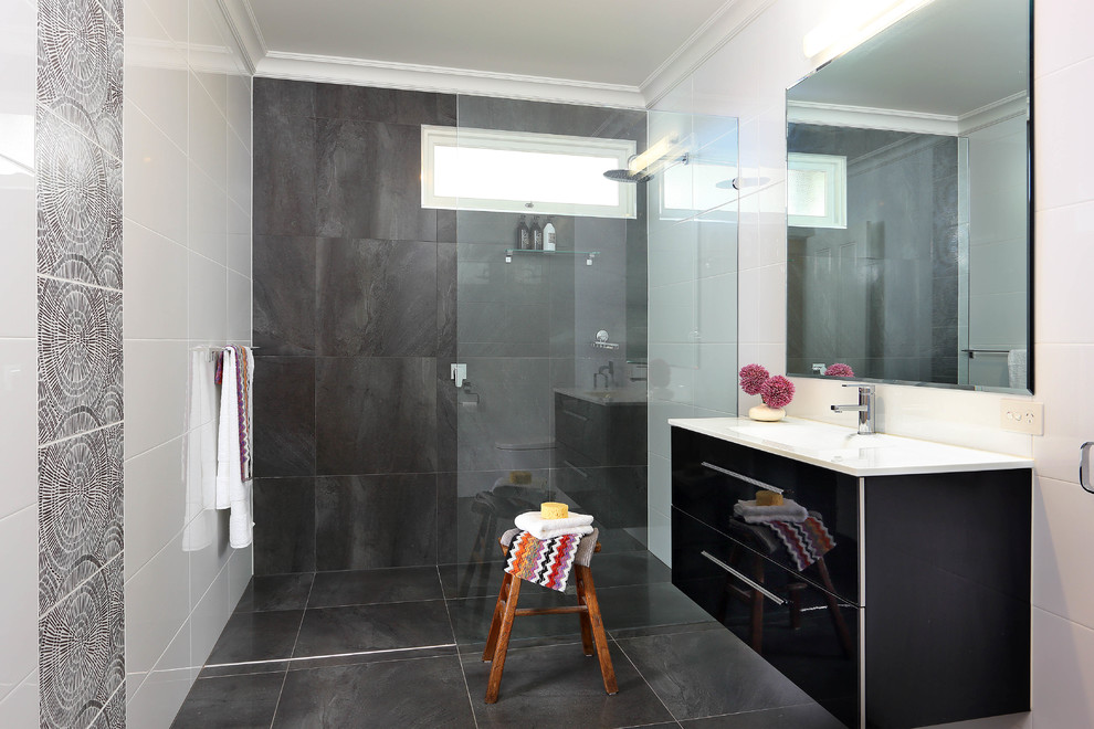 This is an example of a mid-sized modern 3/4 bathroom in Brisbane with an integrated sink, flat-panel cabinets, black cabinets, solid surface benchtops, an open shower, a one-piece toilet, blue tile, porcelain tile, white walls and porcelain floors.