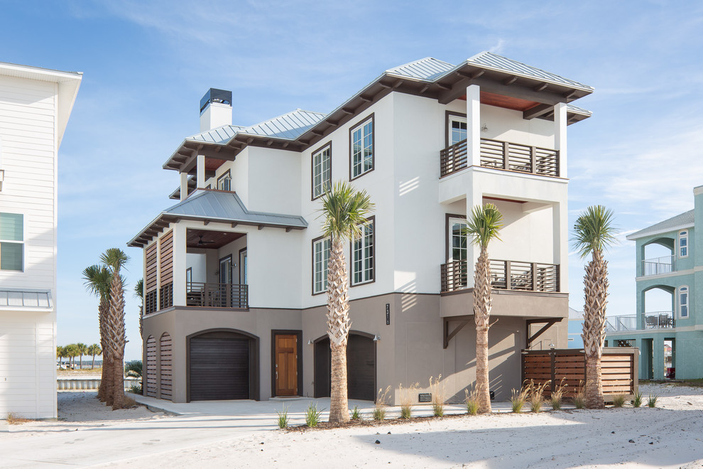 Large beach style three-storey stucco white house exterior in Atlanta with a hip roof and a metal roof.