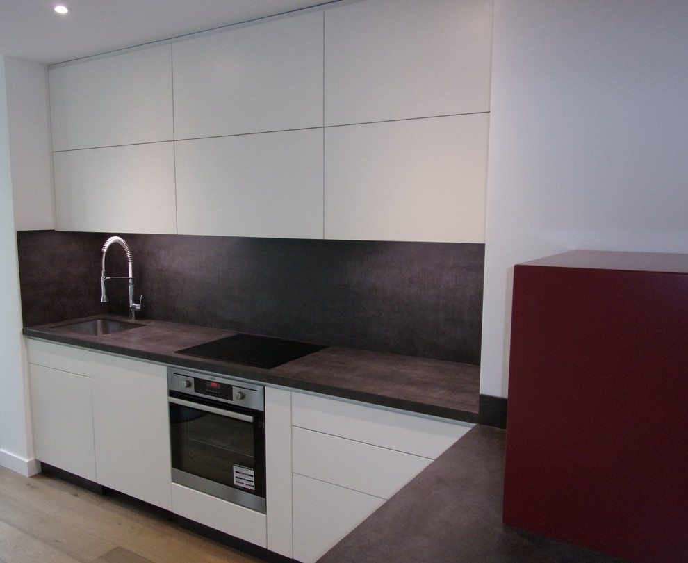 This is an example of a contemporary l-shaped open plan kitchen in Marseille with a single-bowl sink, flat-panel cabinets and white cabinets.