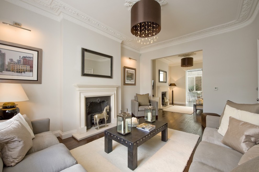 This is an example of a transitional formal enclosed living room in West Midlands with beige walls, dark hardwood floors and a standard fireplace.