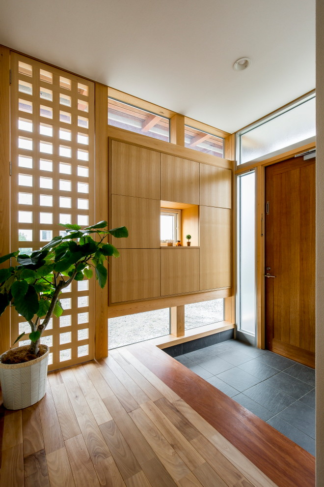 Photo of an asian entryway in Other with a single front door, a medium wood front door and grey floor.