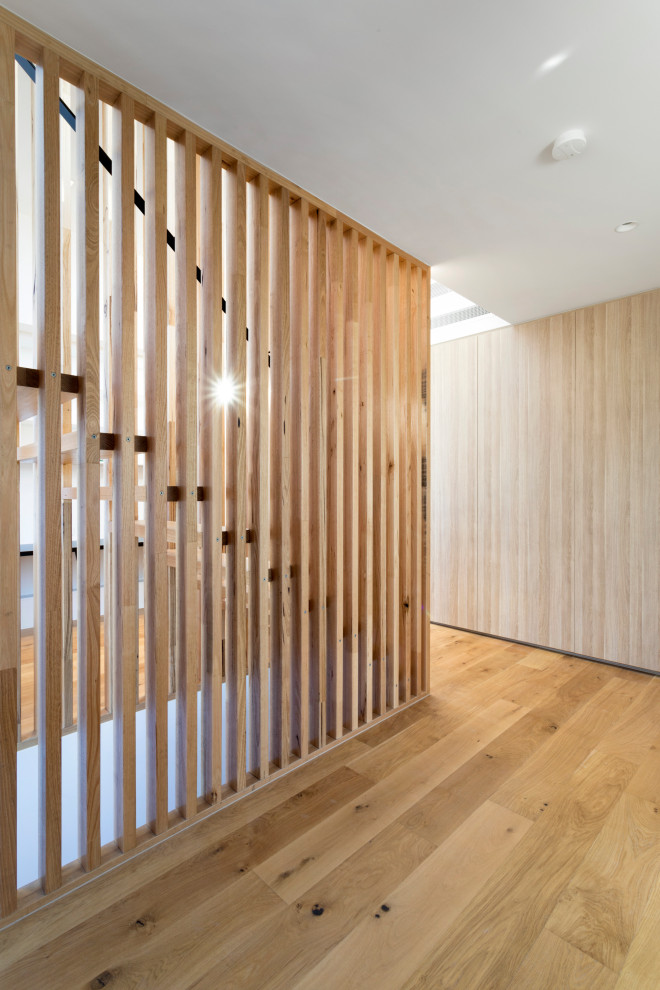 Photo of a mid-sized contemporary wood floating staircase in Melbourne with open risers, metal railing and wood walls.