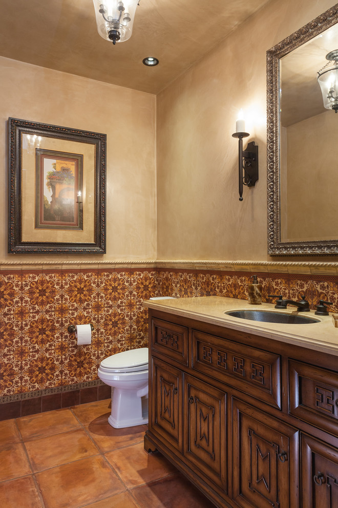 This is an example of a mediterranean bathroom in Orange County with dark wood cabinets, multi-coloured tile, beige walls and terra-cotta floors.