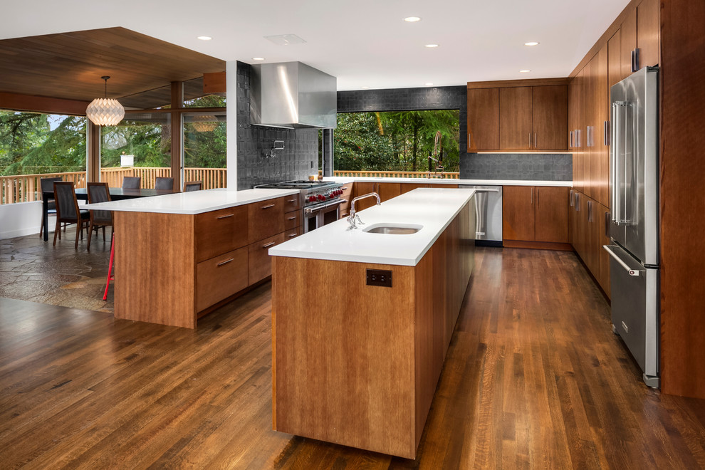 Inspiration for a large midcentury u-shaped open plan kitchen in Seattle with an undermount sink, flat-panel cabinets, light wood cabinets, quartz benchtops, black splashback, cement tile splashback, stainless steel appliances, medium hardwood floors and with island.