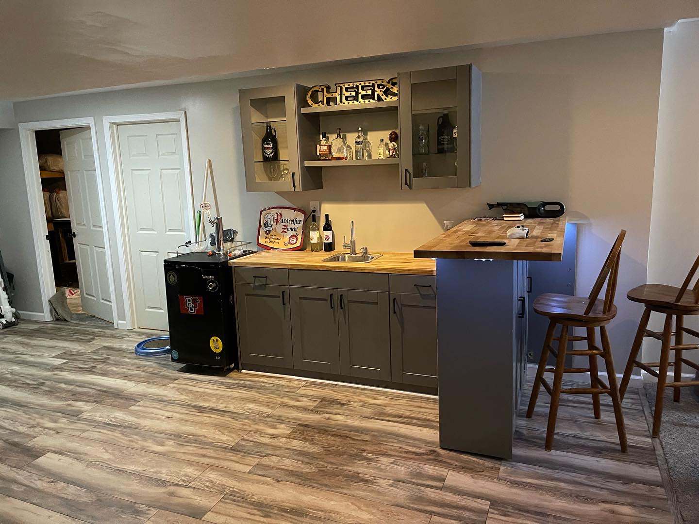 Inspiration for a mid-sized contemporary l-shaped light wood floor and brown floor wet bar remodel in Cleveland with a drop-in sink, shaker cabinets, gray cabinets, wood countertops and brown countert