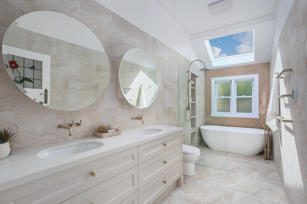 Inspiration for an expansive transitional bathroom in Perth with shaker cabinets, a freestanding tub, an open shower, a two-piece toilet, travertine, an undermount sink, engineered quartz benchtops, an open shower, white benchtops, a double vanity, a freestanding vanity, beige walls, beige floor and a niche.