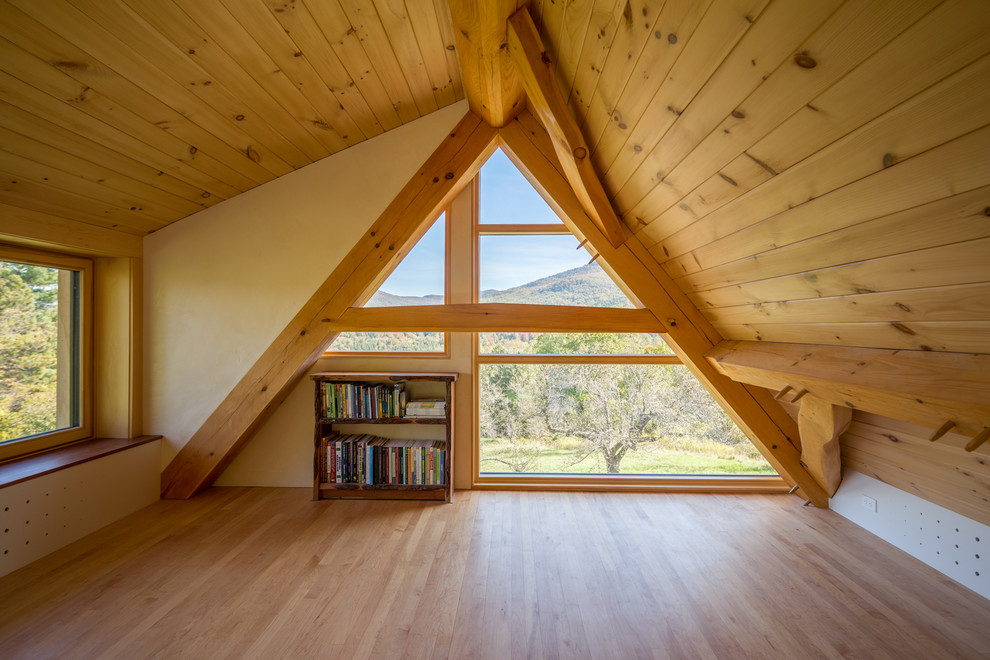 Small country loft-style bedroom in DC Metro with beige walls, light hardwood floors and brown floor.