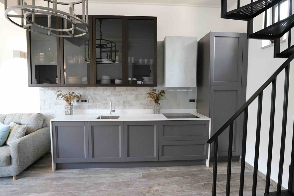 This is an example of a small mediterranean single-wall open plan kitchen in London with a single-bowl sink, shaker cabinets, grey cabinets, quartzite benchtops, grey splashback, stone slab splashback, panelled appliances, slate floors, grey floor and white benchtop.