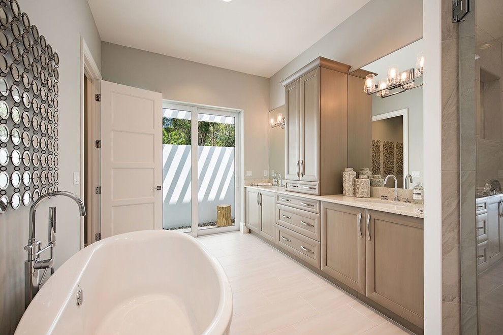 Inspiration for a large contemporary master bathroom in Miami with recessed-panel cabinets, beige cabinets, a drop-in tub, a corner shower, beige tile, limestone, grey walls, light hardwood floors, a drop-in sink, granite benchtops, beige floor, a hinged shower door and multi-coloured benchtops.