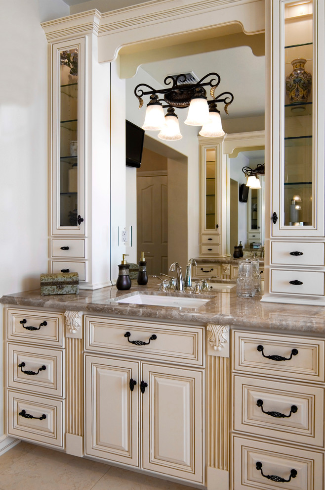 Photo of a mid-sized traditional master bathroom in Los Angeles with raised-panel cabinets, beige cabinets, white walls, ceramic floors, an undermount sink, marble benchtops, beige floor and brown benchtops.