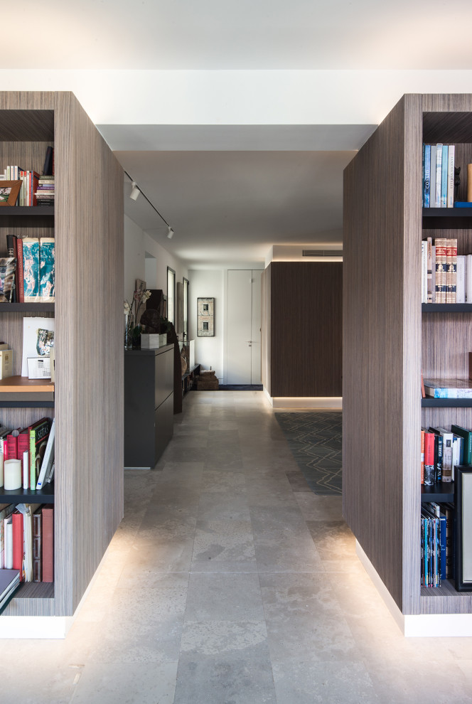 This is an example of a large contemporary open concept living room in Madrid with a library, white walls, limestone floors, grey floor and decorative wall panelling.