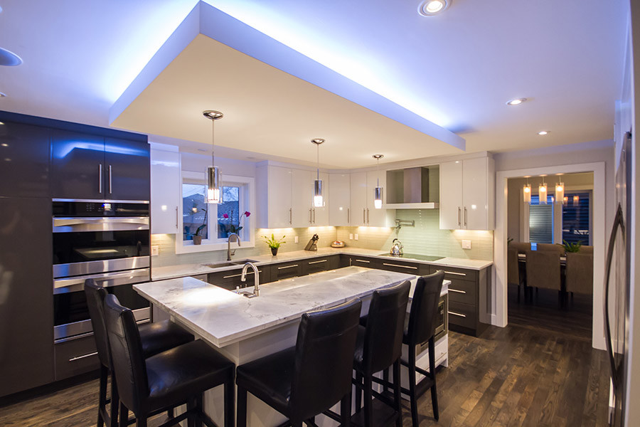 Inspiration for a large transitional l-shaped dark wood floor open concept kitchen remodel with an undermount sink, flat-panel cabinets, white cabinets, granite countertops, green backsplash, glass tile backsplash, stainless steel appliances and an island