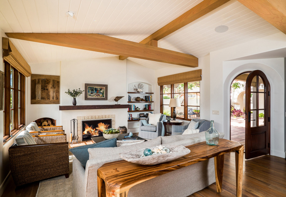 Inspiration for a mid-sized beach style open concept living room in Orange County with white walls, medium hardwood floors, a standard fireplace, a tile fireplace surround and a concealed tv.