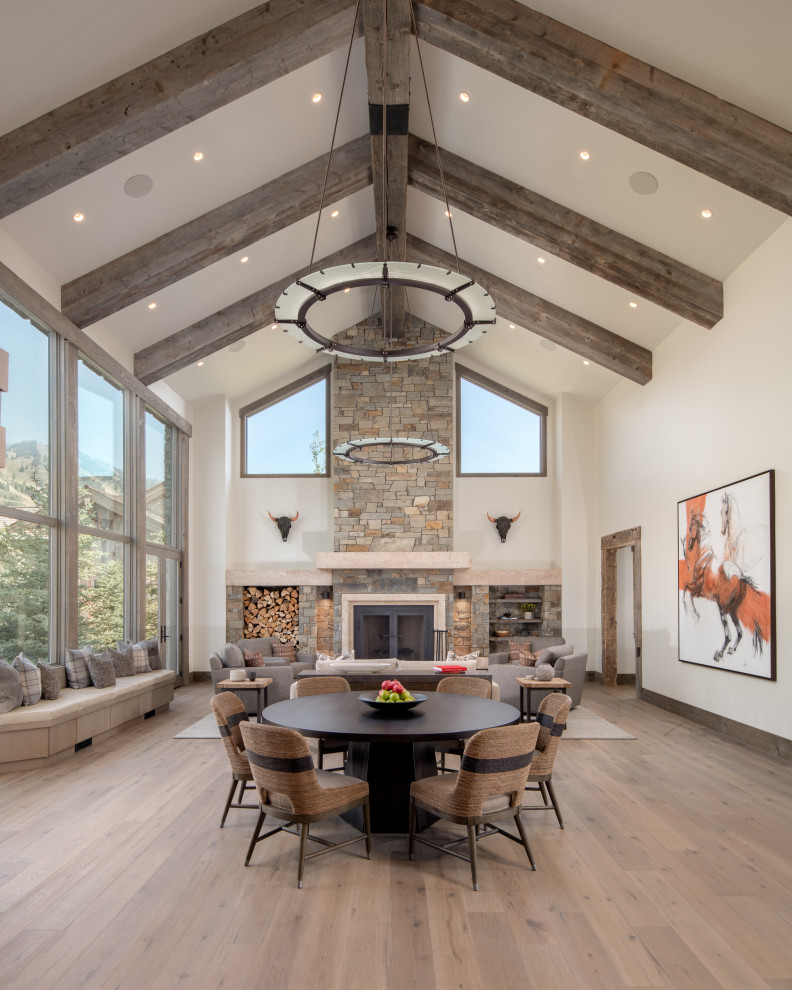 Large country formal open concept living room with light hardwood floors, a stone fireplace surround, white walls, a standard fireplace, no tv and beige floor.