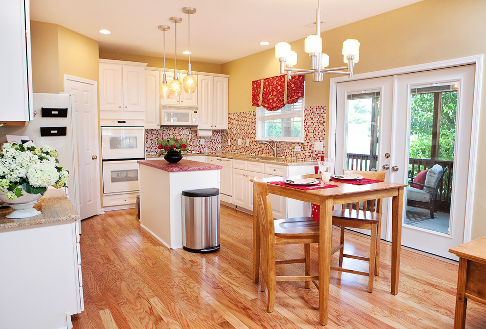 Traditional l-shaped kitchen in Raleigh with a double-bowl sink, raised-panel cabinets, white cabinets, concrete benchtops, red splashback, mosaic tile splashback, white appliances, medium hardwood floors, with island and brown floor.