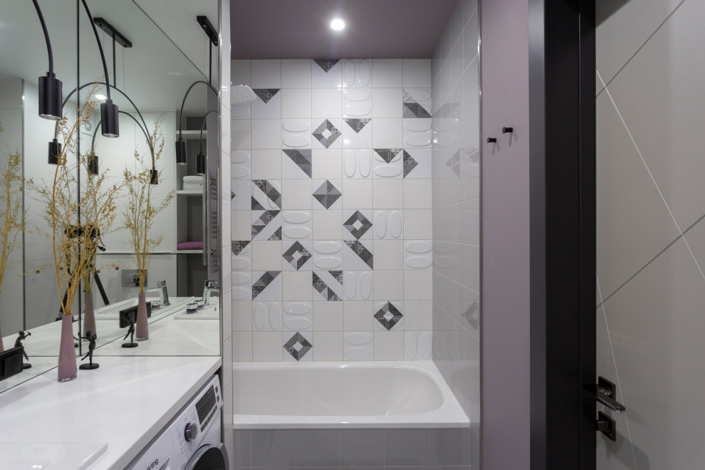 Mid-sized contemporary bathroom in Yekaterinburg with flat-panel cabinets, white cabinets, an alcove tub, a wall-mount toilet, white tile, ceramic tile, purple walls, porcelain floors, solid surface benchtops, white floor, white benchtops, a laundry, a single vanity and a drop-in sink.